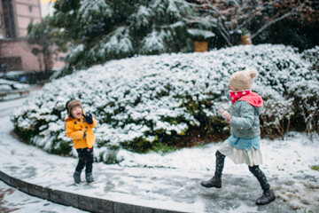 A young girl and boy play in the snow