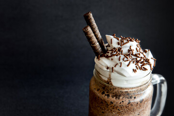 Cold frappe coffee with whipped cream. Black background with iced frappuccino.