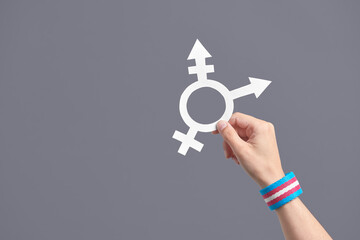 Hand holding a symbol of the transgender community with a trans flag bracelet - obrazy, fototapety, plakaty