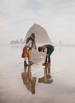 3 young children explore a hazy sunset beach with wet sand reflection