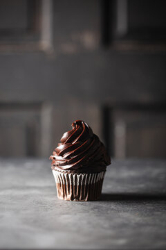 Solitary chocolate cupcake with rich chocolate frosting swirls