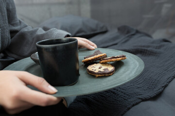 Woman with cup of tea near black table
