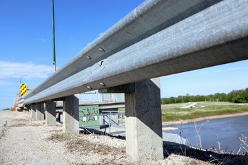 Close-up of a gray concrete and steel road fence. The river is in the background