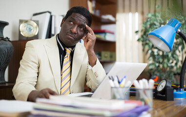 Portrait of pensive african american man working in modern office, solving business issues. Daily work routine and responsibilities concept
