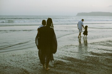 Family wading in ocean at dusk