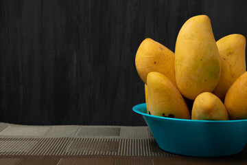 Mangos manila maduros en un plato azul con un fondo de color negro