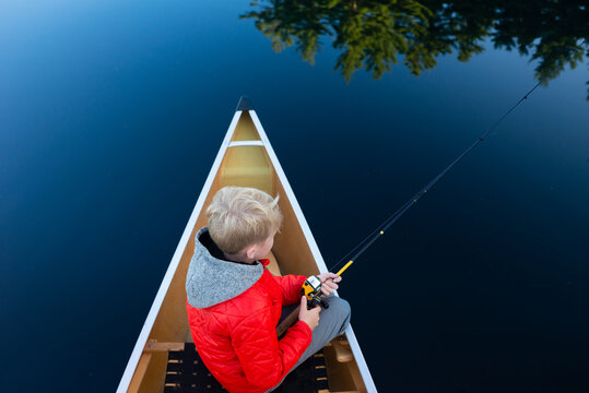 Boy enjoys quiet fishing vacation on Muskoka lake in canoe