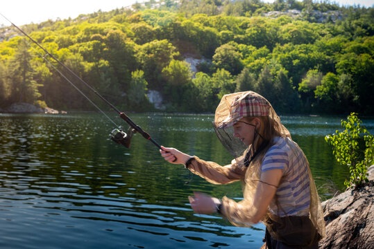 Girl Fishing at Lake wearing Bug Jacket with Mountain Ridge on Back Country Family Camping Trip
