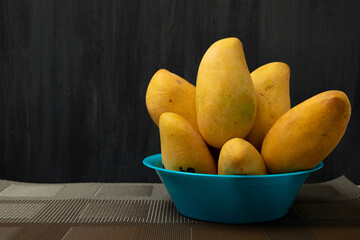 Mangos manila maduros en un plato azul con un fondo de color negro