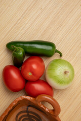 chiles, cebolla y jitomates para hacer salsa Mexicana sobre una mesa