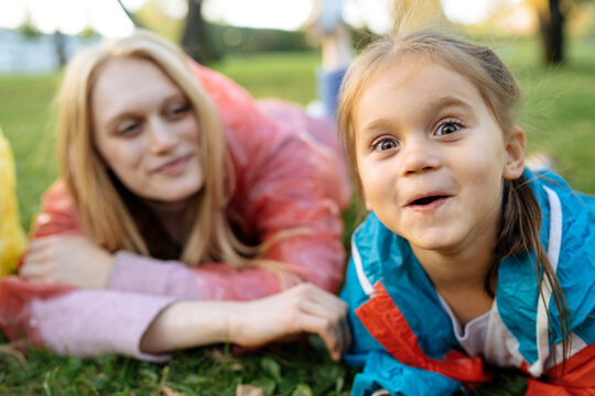 A Child With A Funny Expression Lies On The Lawn