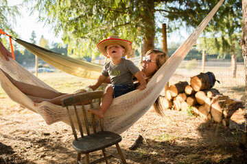 Toddler climbs into hammock with his mother