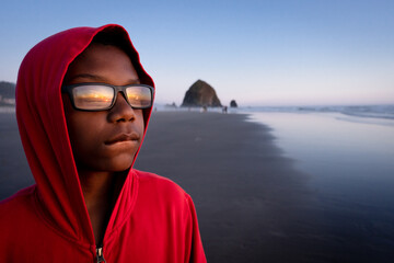 Young Black boy in red hoodie watches sunset
