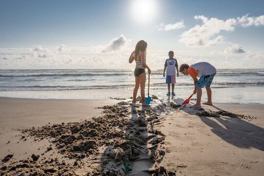 Three Children dig a trench at beach
