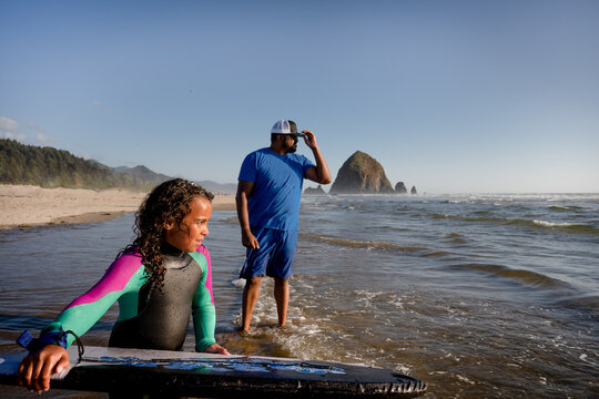 Girl And Father Boogie Boarding At Beach