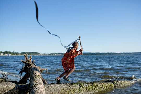 Boy with long ribbon flag runs down boat launch at waterfront