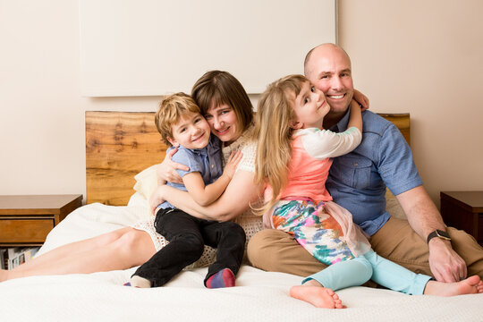 Family snuggles on a bed for photo session