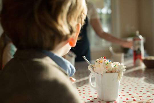 Mug overflowing with whipped cream and sprinkles sits on polka dot table cloth
