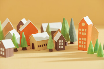 Handmade small houses with pine trees on a yellow background