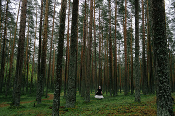 woman in vintage costume stands in the woods
