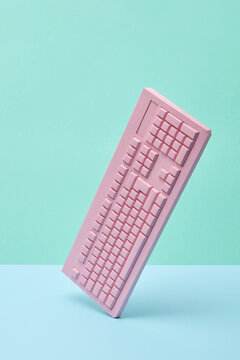 Vertically balancing papercraft pink keyboard.