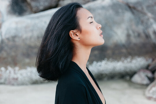 Asian woman wrapping in kimono against cliff on seashore