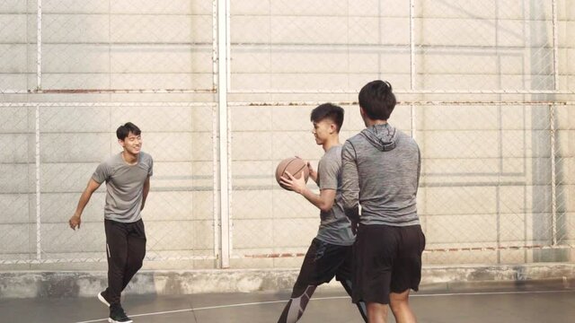 group of young asian men playing basketball for fun on outdoor court