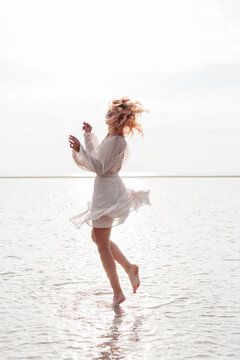 Happy woman in white dress enjoying summer day on beach