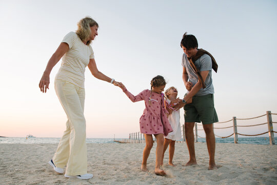 Two girls with their father and grandmother on the beach - Powered by Adobe