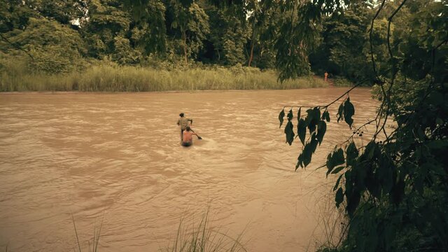 people crossing the river on a dugout canoe in deep jungle