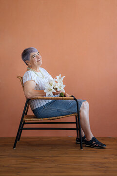 elegant elderly woman with a bouquet sits on a chair