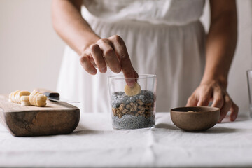 Anonymous Woman Decorating Chia Pudding With Fresh Banana And Homemade Granola