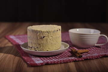 A buttercream cake and a cup of coffee with cinnamon sticks.