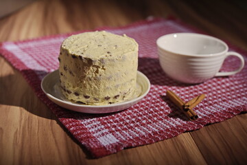 A buttercream cake and a cup of coffee with cinnamon sticks.