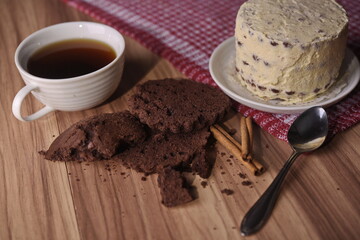 Brownie slices, buttercream cake, and a cup of coffee with cinnamon sticks on the table.