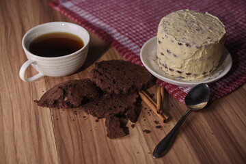Brownie slices, buttercream cake, and a cup of coffee with cinnamon sticks on the table.