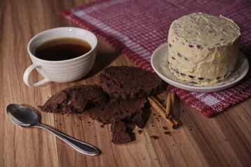 Brownie slices, buttercream cake, and a cup of coffee with cinnamon sticks on the table.