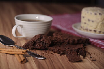 Brownie slices, buttercream cake, and a cup of coffee with cinnamon sticks on the table.