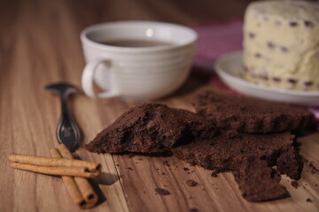 Brownie slices, buttercream cake, and a cup of coffee with cinnamon sticks on the table.