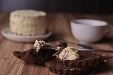 Brownie slices with a slice of buttercream on a knife on the background of the finished cake on the table.