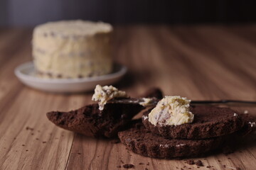 Brownie slices with a slice of buttercream on a knife on the background of the finished cake on the table.