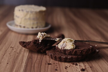 Brownie slices with a slice of buttercream on a knife on the background of the finished cake on the table.