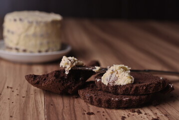 Brownie slices with a slice of buttercream on a knife on the background of the finished cake on the table.