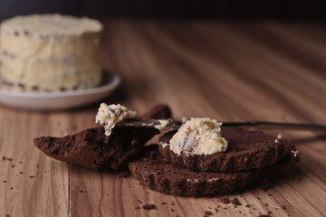 Brownie slices with a slice of buttercream on a knife on the background of the finished cake on the table.
