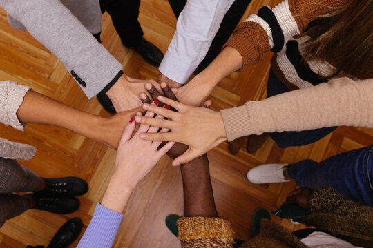 Company of diverse friends stacking hands together