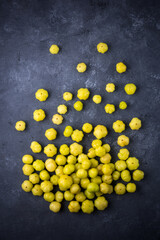 star gooseberry or starberry, also known as malay or country or west india or tahitian gooseberry, small star shaped waxy yellow tropical berries fruit scattered on a black textured background