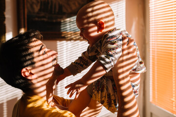 Father and baby playing by the window morning light