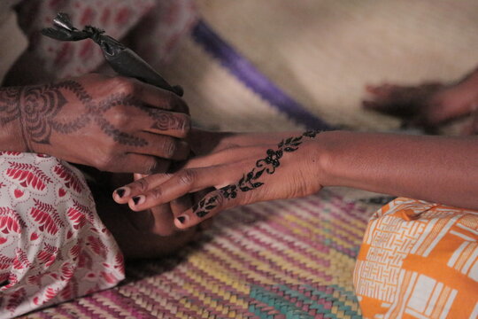 Henna Artist painting a lady's hand