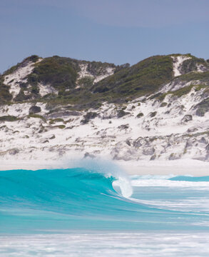 Blue, Turquoise Wave Breaking, Sand Dunes In The Background