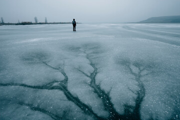Desolate winter landscape with man on frozen lake
